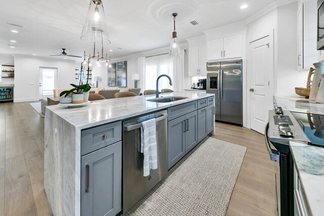 kitchen featuring ceiling fan, pendant lighting, an island with sink, appliances with stainless steel finishes, and sink