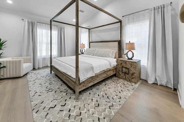 bedroom with light hardwood / wood-style floors, multiple windows, and lofted ceiling