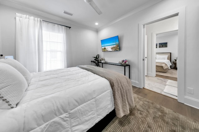 bedroom featuring hardwood / wood-style floors, ornamental molding, and ceiling fan