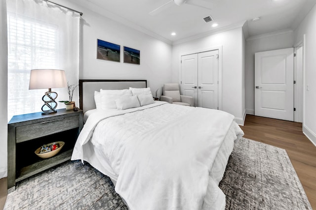 bedroom featuring ceiling fan, a closet, hardwood / wood-style floors, and ornamental molding