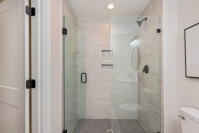 bathroom featuring toilet and a shower with door