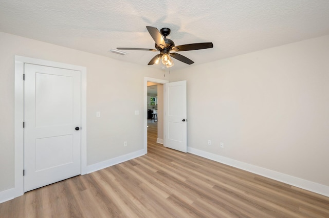 unfurnished room with a textured ceiling, ceiling fan, and light wood-type flooring