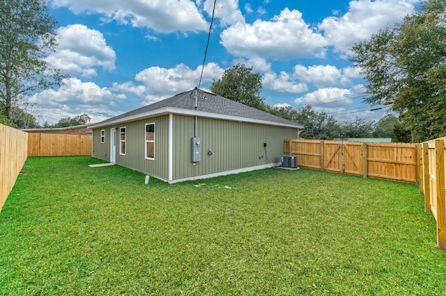 back of house with central AC and a lawn