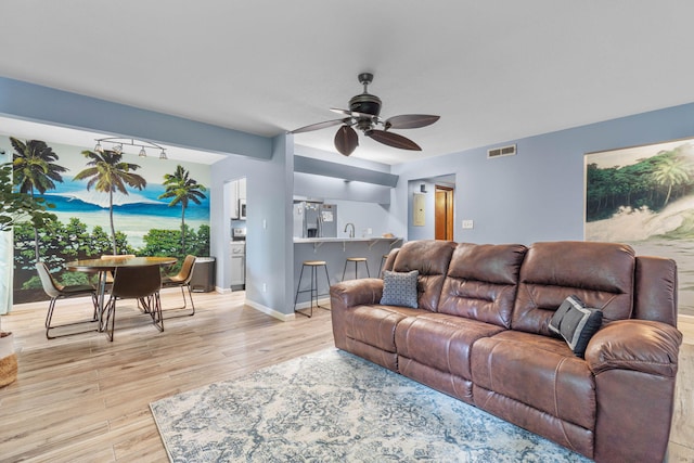 living area featuring light wood-style floors, visible vents, baseboards, and a ceiling fan