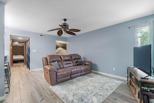 living area featuring a ceiling fan, baseboards, visible vents, and wood finished floors