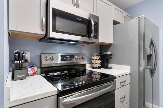 kitchen with stainless steel appliances, light countertops, and white cabinetry