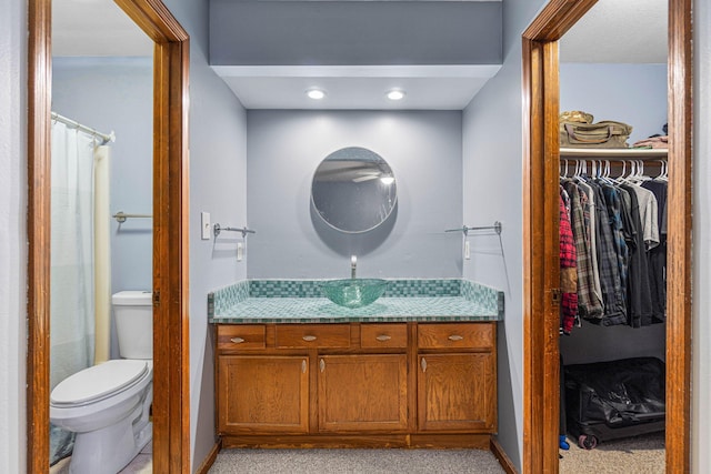 full bathroom featuring vanity, a walk in closet, and toilet