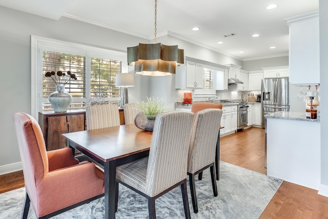 dining area featuring ornamental molding and light hardwood / wood-style flooring