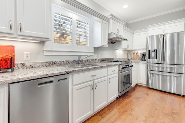 kitchen featuring stainless steel appliances, light stone countertops, white cabinets, ornamental molding, and sink