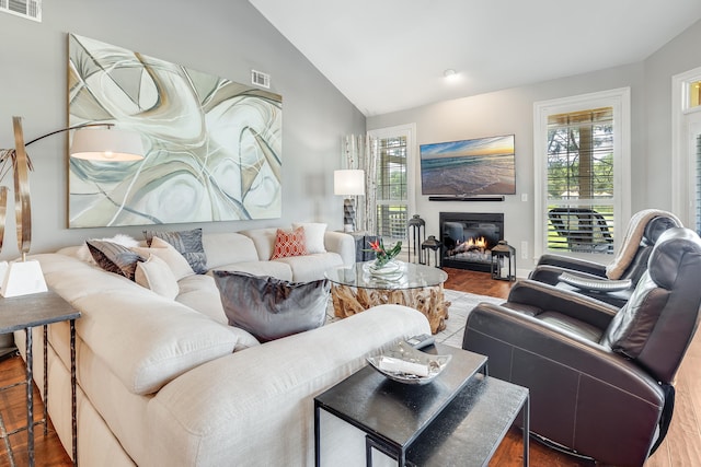 living room featuring lofted ceiling, wood-type flooring, and plenty of natural light