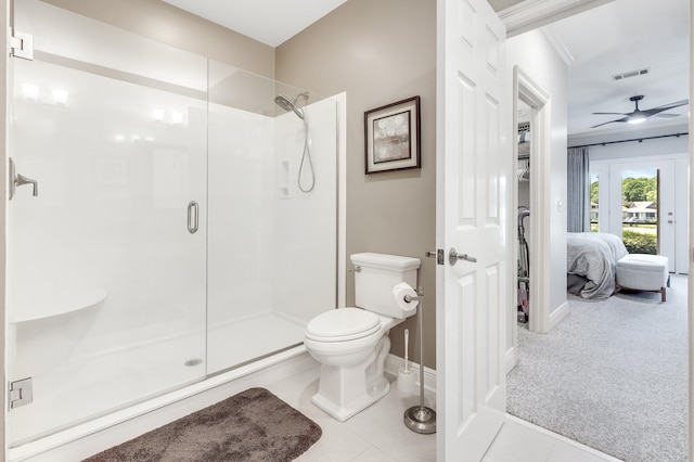 bathroom featuring tile patterned floors, toilet, crown molding, and a shower with shower door