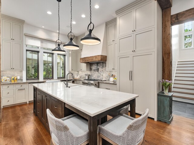 kitchen featuring backsplash, decorative light fixtures, high end stove, and wood-type flooring