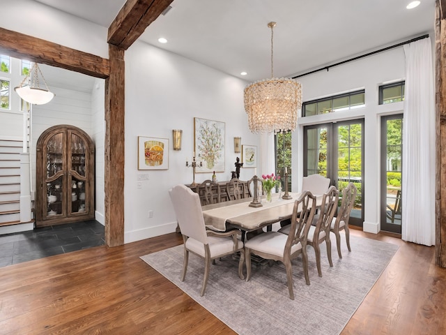 dining room with a wealth of natural light, dark wood-type flooring, an inviting chandelier, and french doors