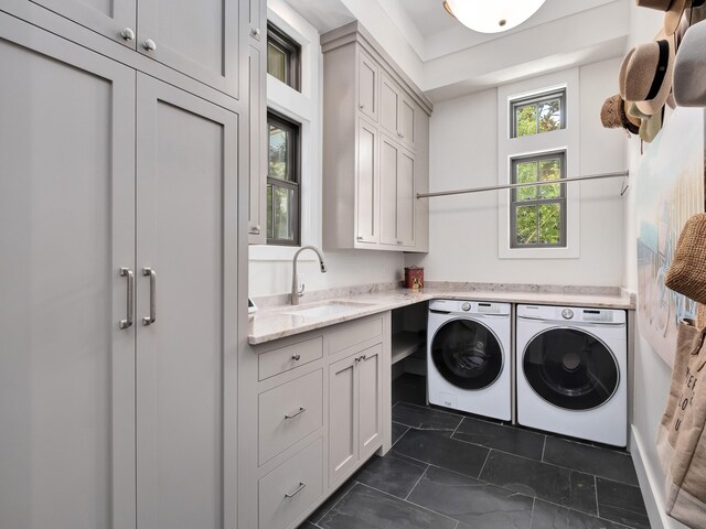 clothes washing area featuring sink, dark tile patterned flooring, separate washer and dryer, and cabinets