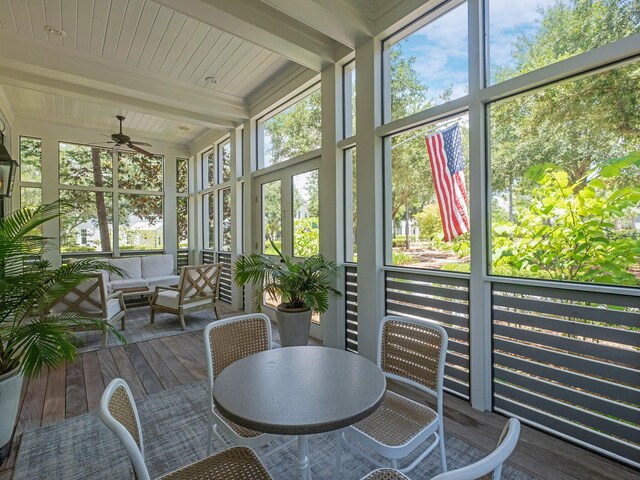 sunroom featuring plenty of natural light, ceiling fan, and beam ceiling