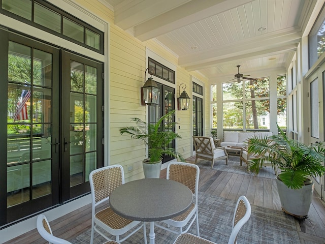 sunroom with ceiling fan, beam ceiling, plenty of natural light, and french doors