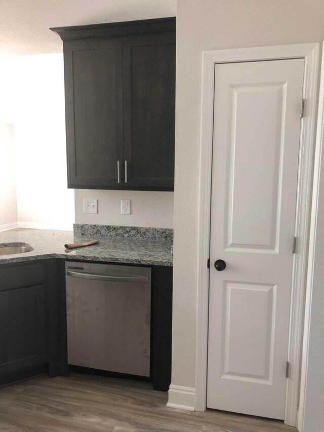 kitchen featuring dishwasher, light stone countertops, and wood-type flooring