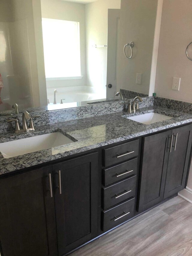 bathroom featuring a bathtub, double sink vanity, and wood-type flooring