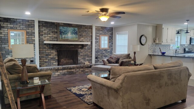 living room featuring a fireplace, ornamental molding, wood-type flooring, sink, and ceiling fan