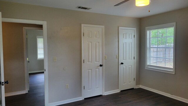 unfurnished bedroom featuring multiple closets, dark hardwood / wood-style flooring, and ceiling fan