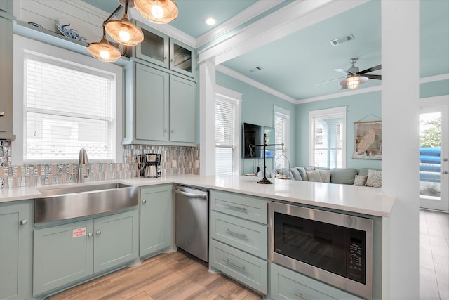 kitchen featuring sink, light wood-type flooring, ornamental molding, and stainless steel appliances