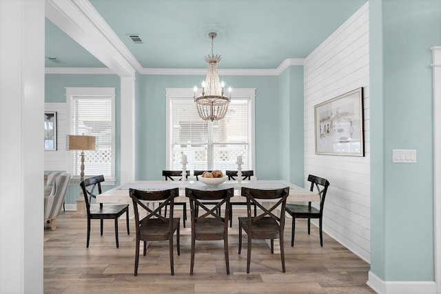 dining room with a chandelier, ornamental molding, and light wood-type flooring