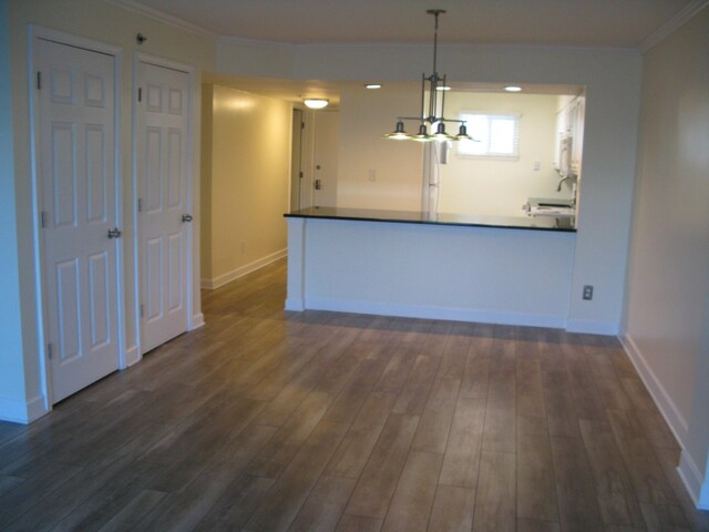 kitchen with crown molding, dark wood finished floors, hanging light fixtures, and baseboards