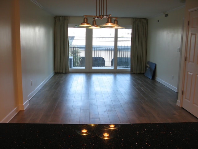 unfurnished dining area featuring dark wood-style floors, plenty of natural light, baseboards, and crown molding