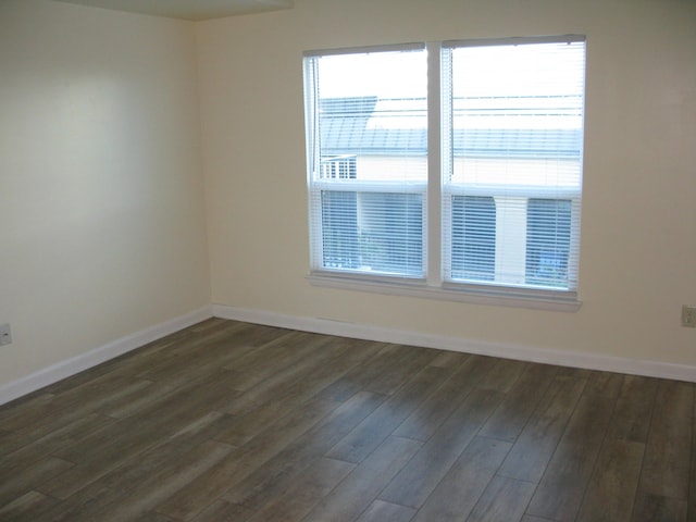 unfurnished room featuring dark wood-type flooring, a wealth of natural light, and baseboards