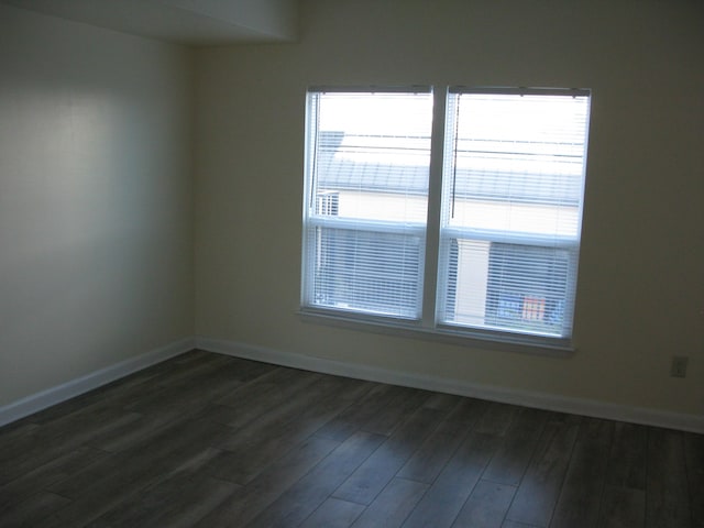 unfurnished room featuring dark wood-type flooring and baseboards