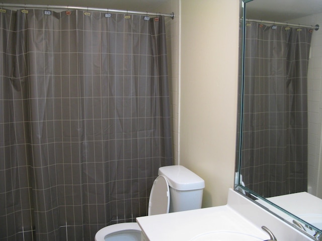 full bath with curtained shower, vanity, and toilet