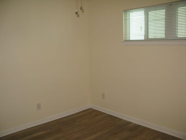 empty room with dark wood-style floors and baseboards