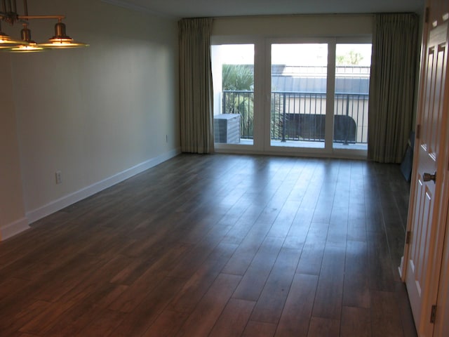 empty room featuring baseboards, dark wood-style flooring, and ornamental molding