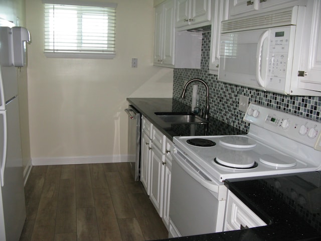 kitchen featuring white appliances, dark countertops, a sink, and white cabinets