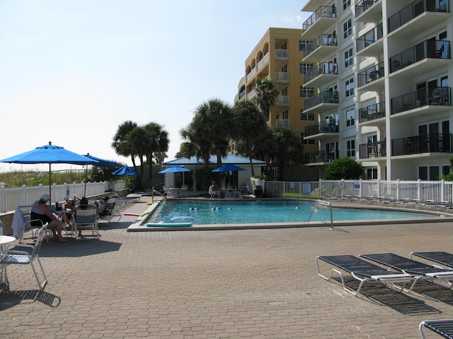 community pool with a patio area and fence