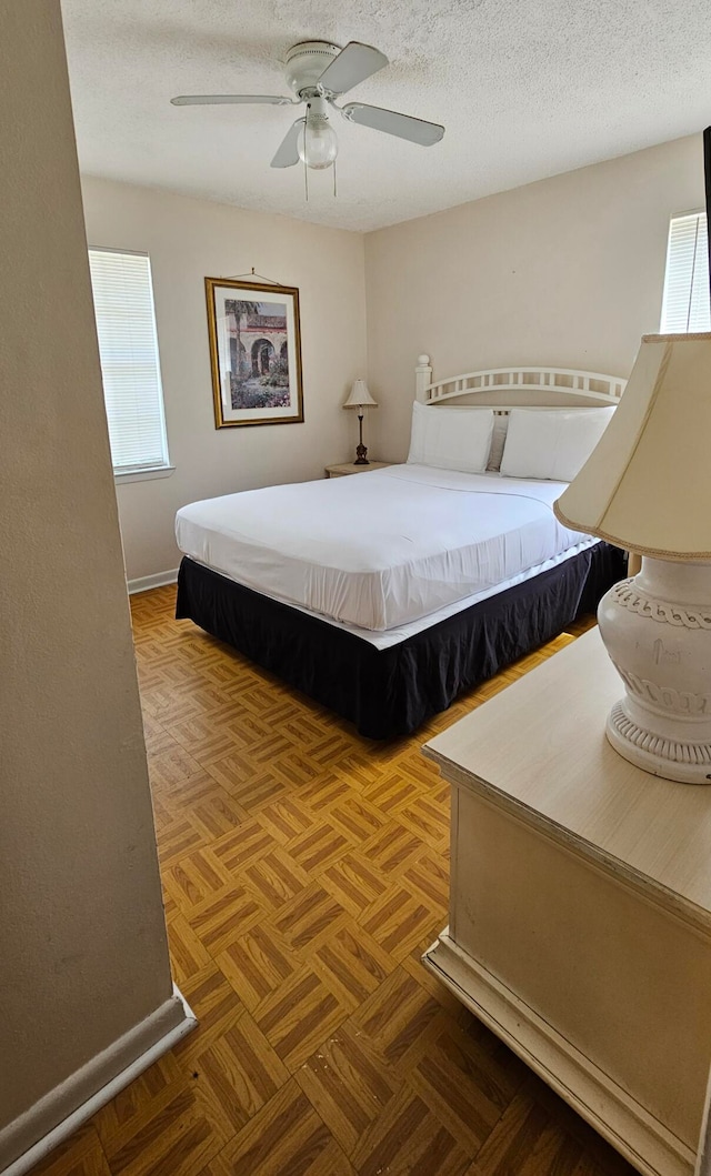 bedroom with a textured ceiling, ceiling fan, and parquet floors