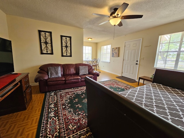 living room with ceiling fan, a wealth of natural light, parquet floors, and a textured ceiling