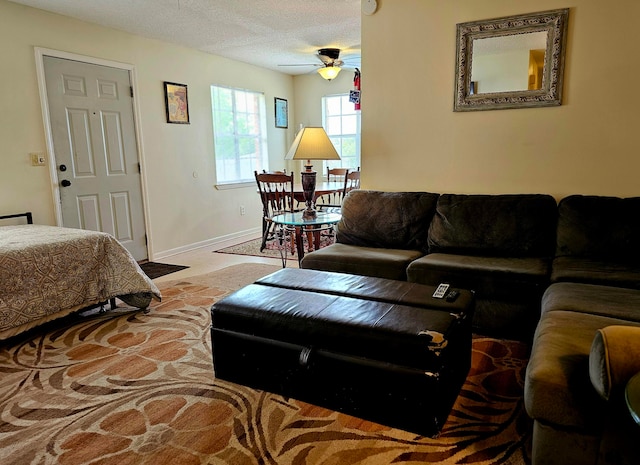 bedroom with ceiling fan, light colored carpet, and a textured ceiling