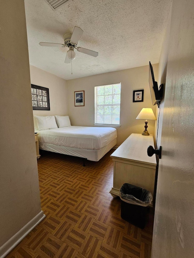 bedroom with a textured ceiling, ceiling fan, and dark parquet flooring