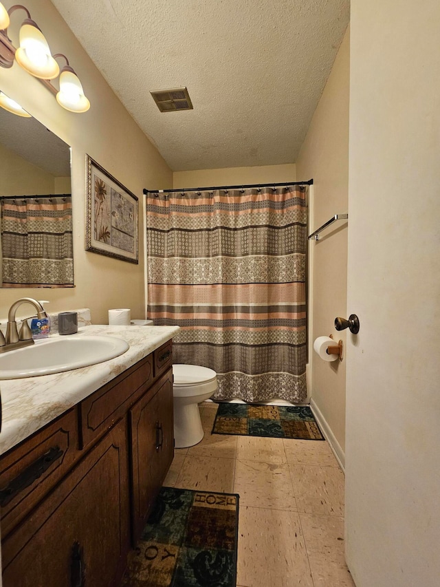 bathroom with tile patterned floors, a textured ceiling, vanity, and toilet