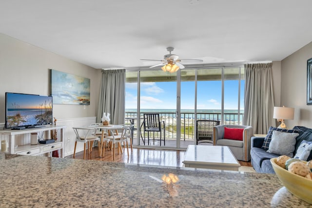 living room featuring ceiling fan, floor to ceiling windows, hardwood / wood-style floors, and a water view