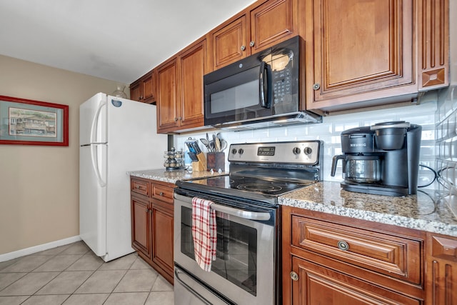 kitchen featuring electric range, white fridge, light stone counters, tasteful backsplash, and light tile patterned floors