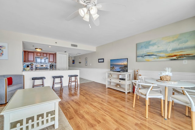 living room with light hardwood / wood-style floors, sink, and ceiling fan