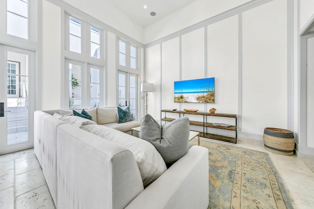 living area featuring recessed lighting, baseboards, and a high ceiling