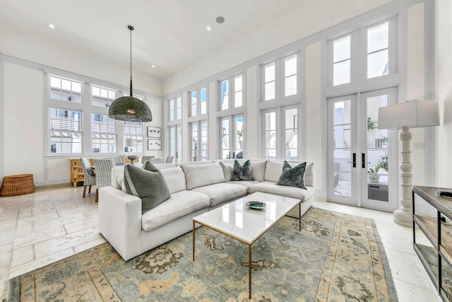 living room featuring recessed lighting, french doors, a towering ceiling, and baseboards