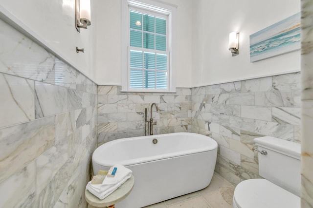 bathroom featuring a freestanding tub, tile walls, and toilet