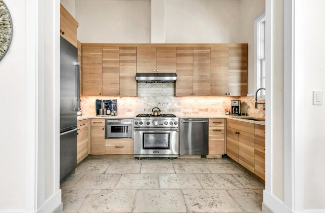 kitchen featuring stainless steel appliances, backsplash, a sink, and under cabinet range hood