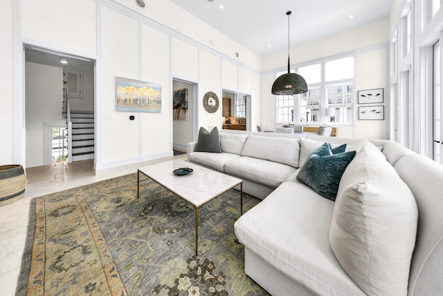 living area featuring stairs, a high ceiling, and recessed lighting