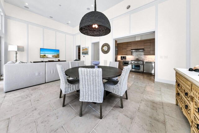 dining space featuring stone tile floors and a high ceiling