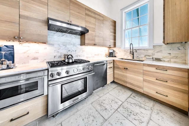 kitchen with under cabinet range hood, stainless steel appliances, a sink, light brown cabinetry, and tasteful backsplash